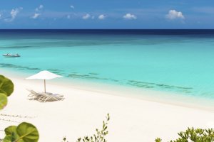 foto sonnenliegen am weissen strand vom luxuriösen modernen designer hotel und resort auf den turks- und caicosinseln in der karibik mit dem türkis farbenen ozean wasser davor 